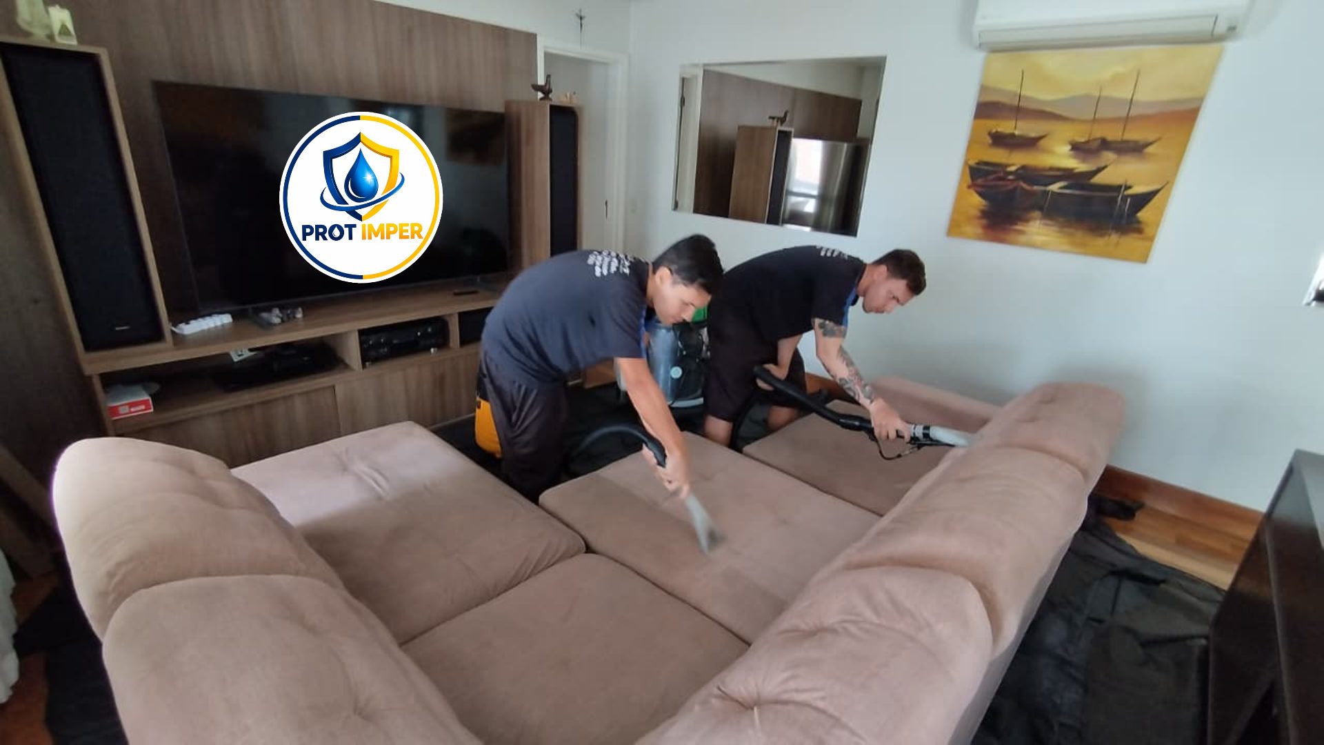 Dois técnicos da PROT IMPER higienizando um sofá retrátil de tecido em atendimento